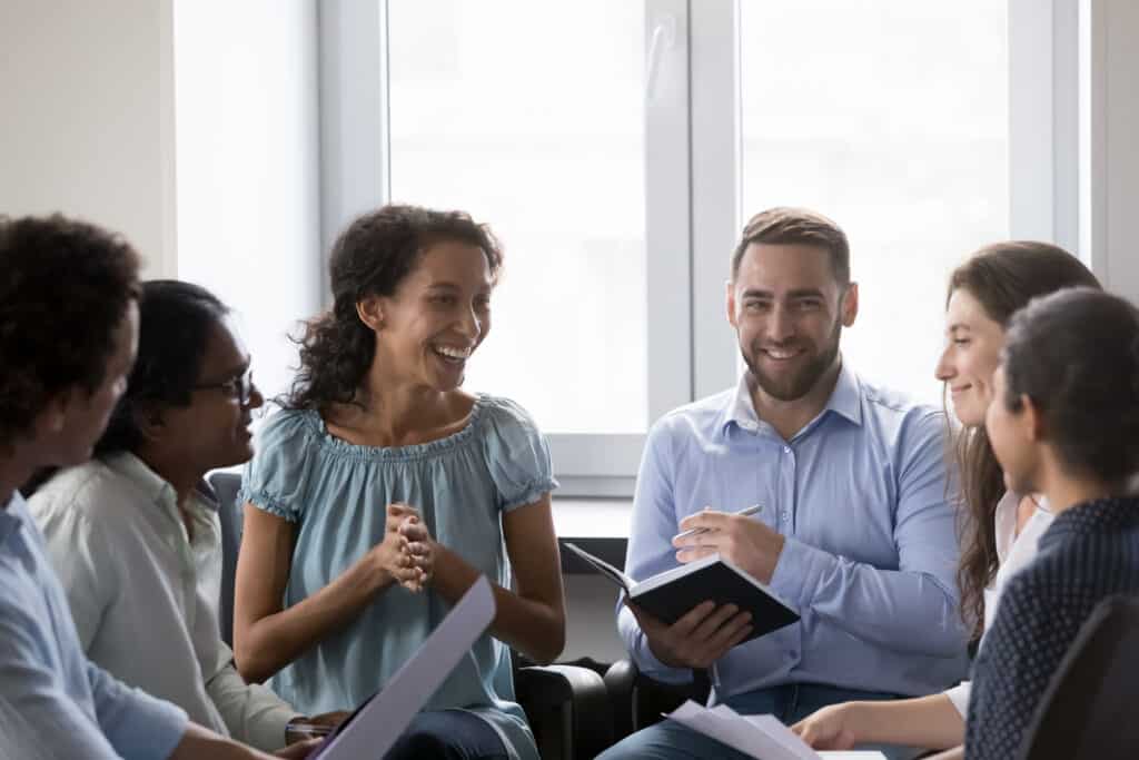 Smiling Multiracial Colleagues Take Part In Motivational Training At Workplace