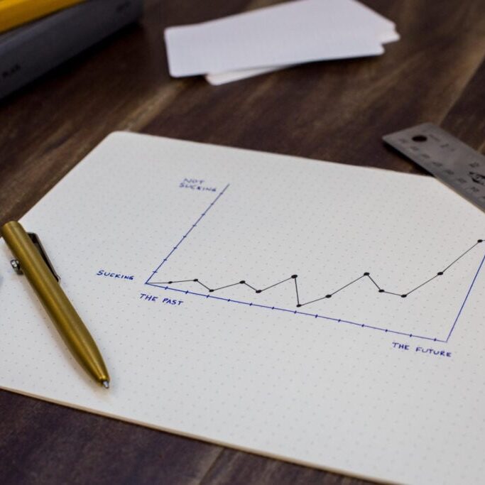 A piece of paper with a hand-drawn graph and a pen sit on a table.